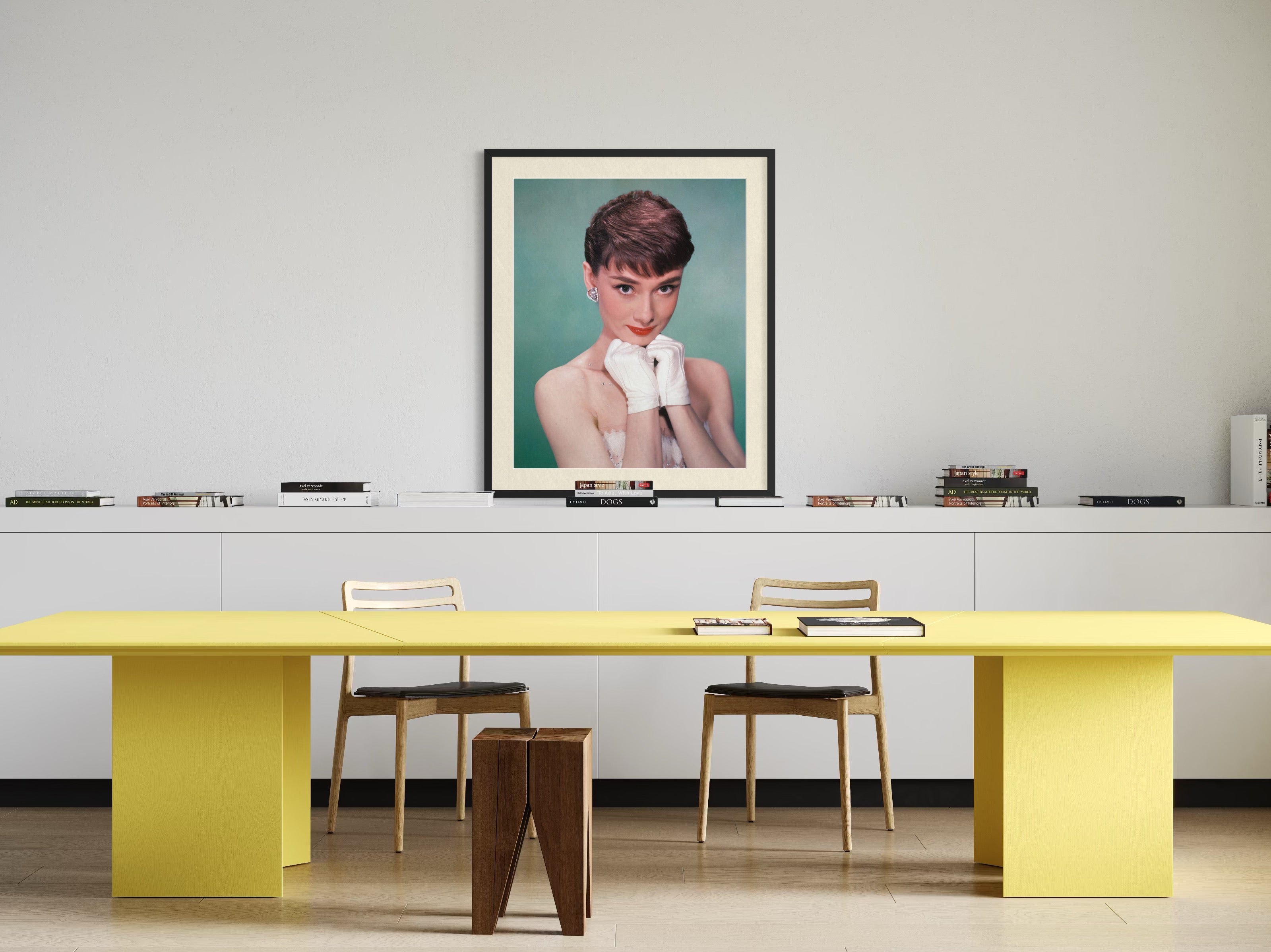 Modern office with a yellow desk, chairs, and a framed portrait of audrey hepburn on the wall.