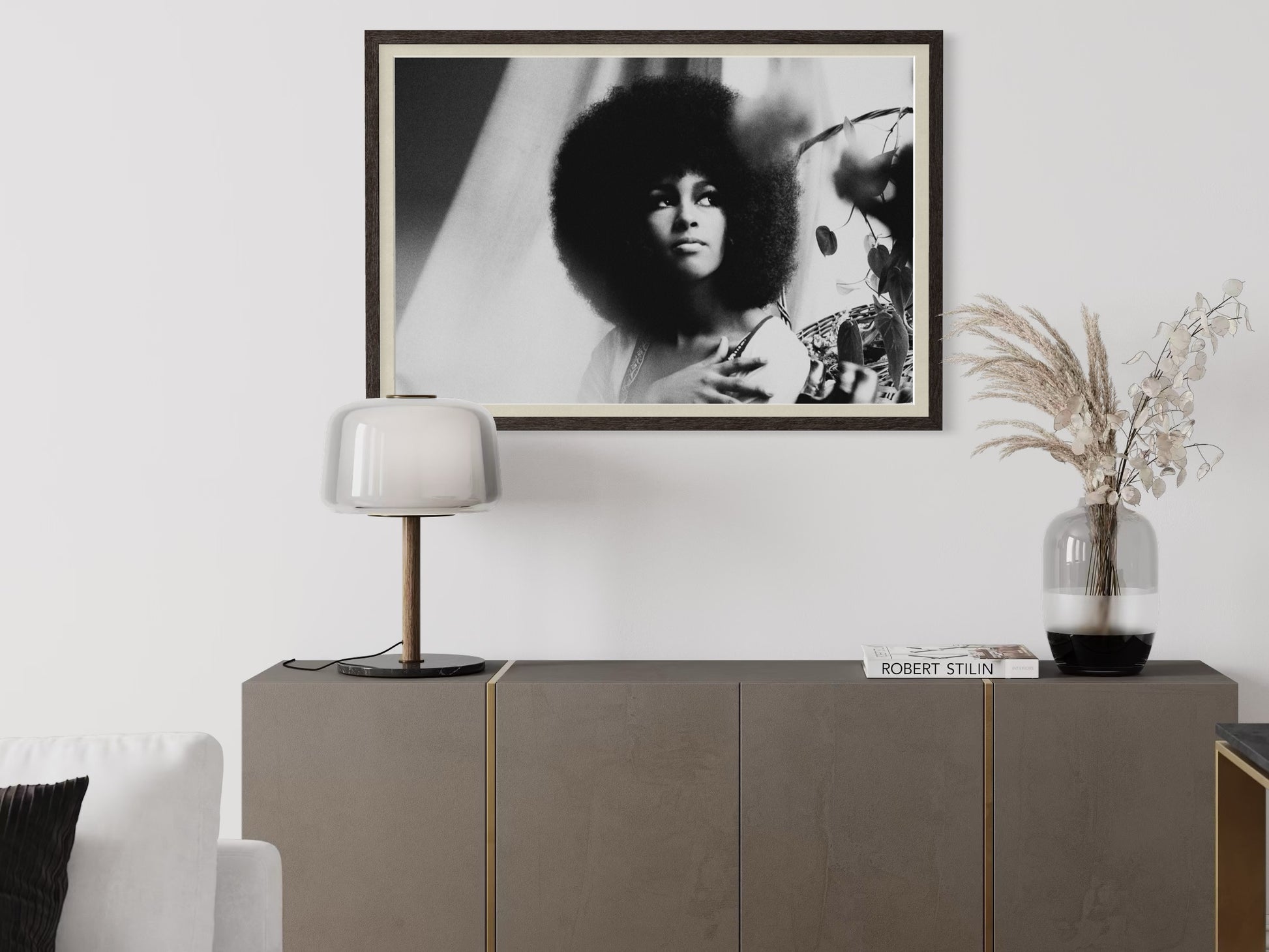 Framed black and white portrait above a sideboard with decorative items.