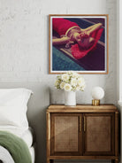 Framed artwork above a wooden cabinet with decorative items in a bedroom setting.