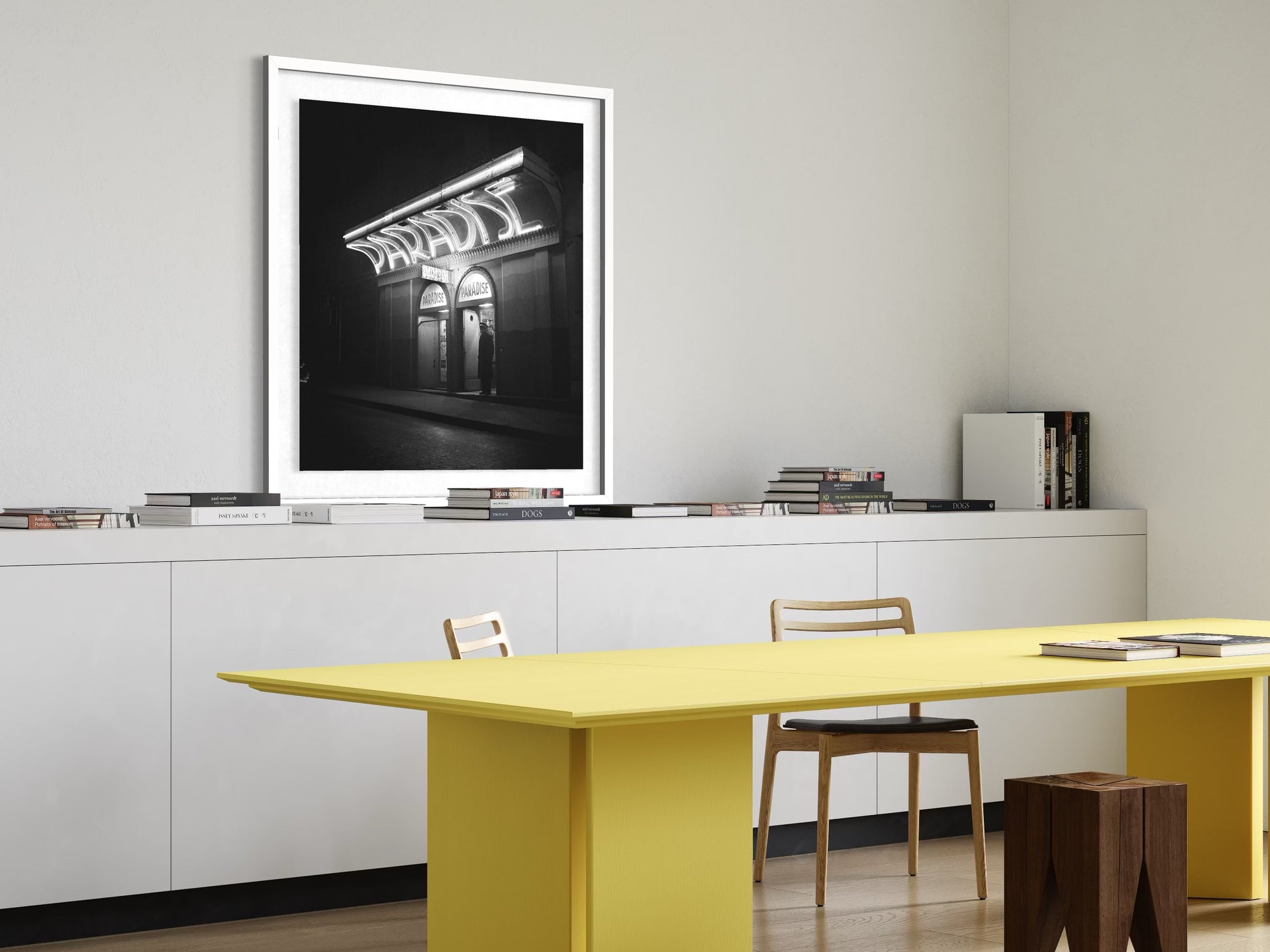 Modern office setup with a yellow table, white cabinets, and framed artwork on the wall.