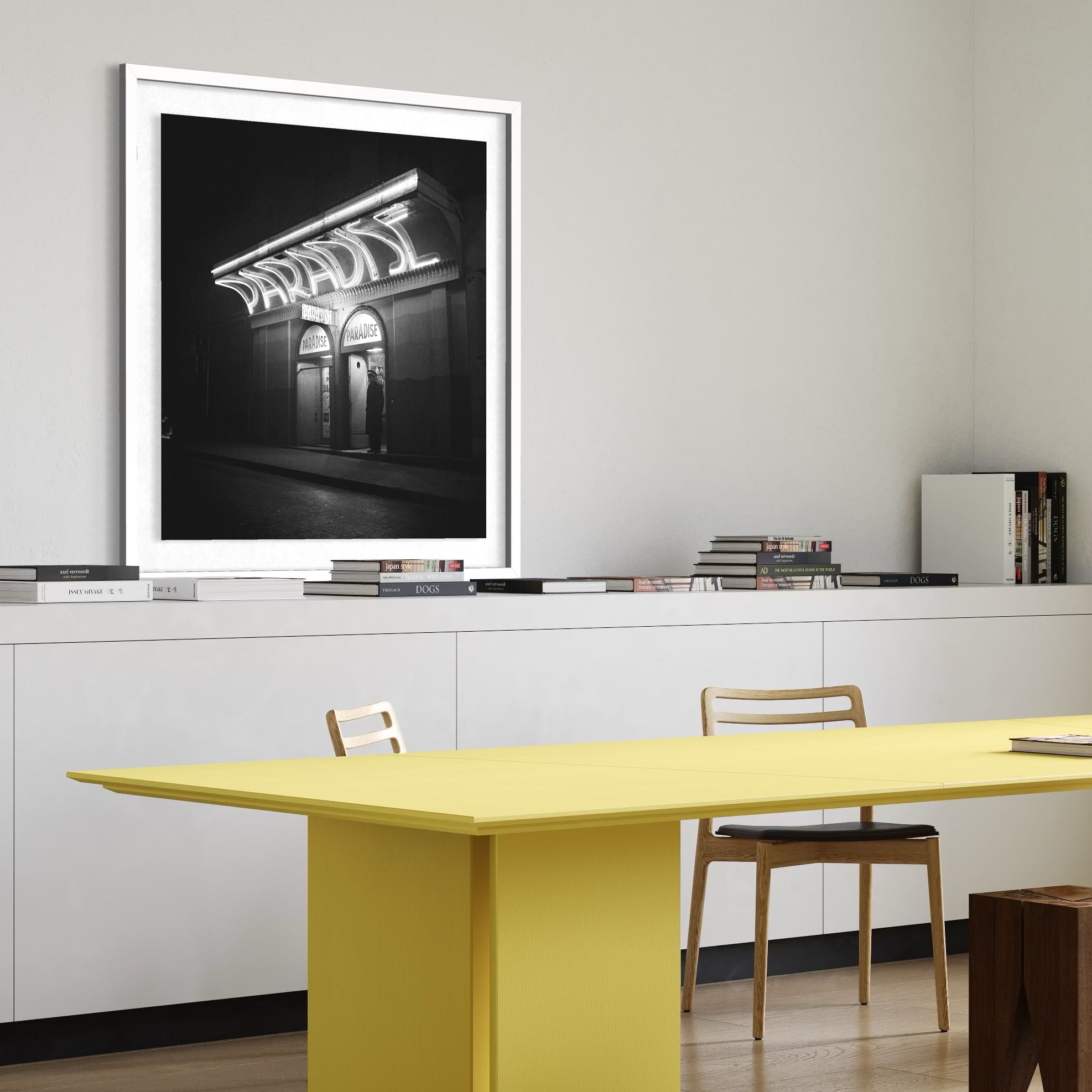 Modern office setup with a yellow table, white cabinets, and framed artwork on the wall.
