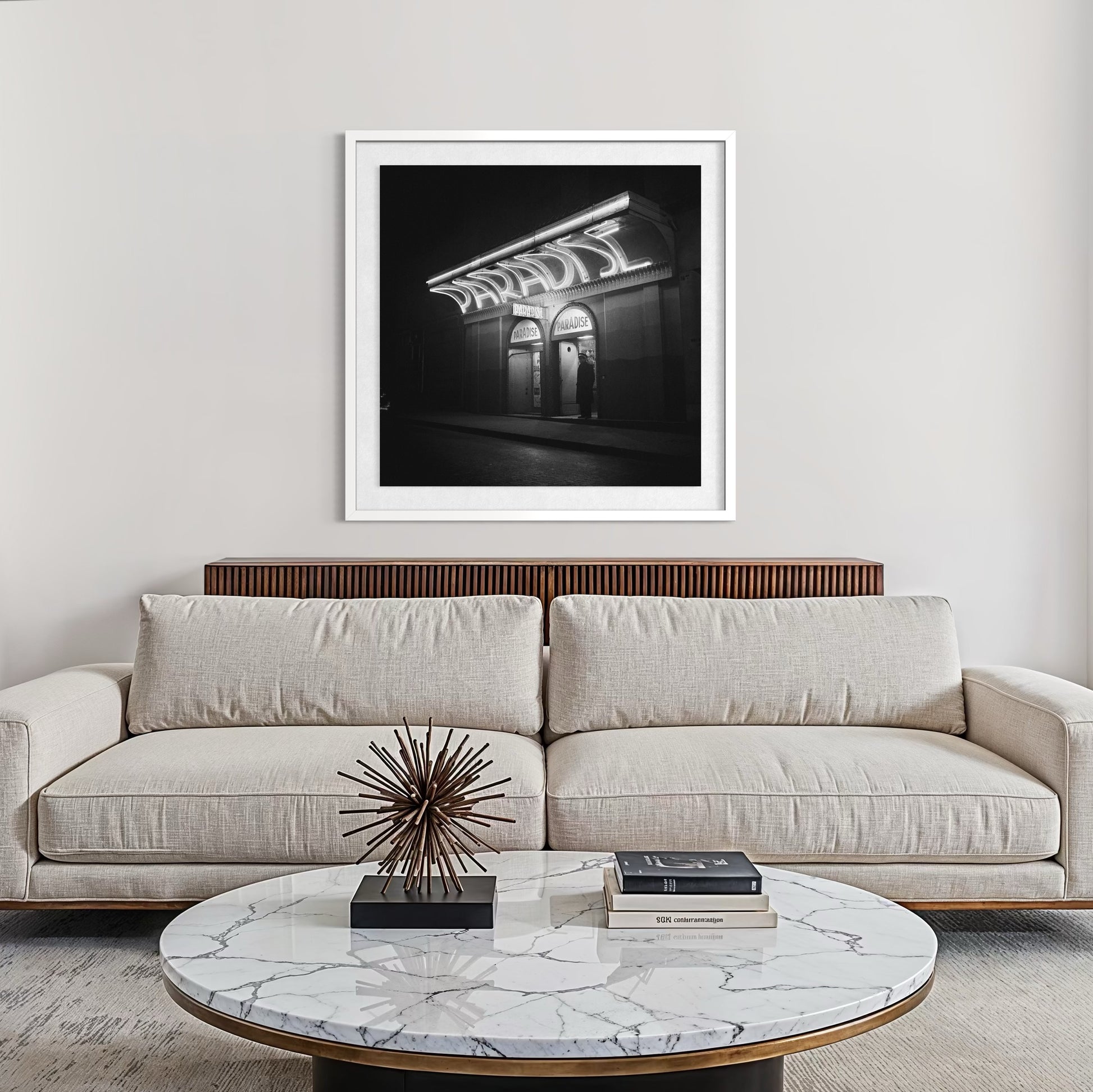 Modern living room with a beige sofa, marble coffee table, and framed black and white artwork.