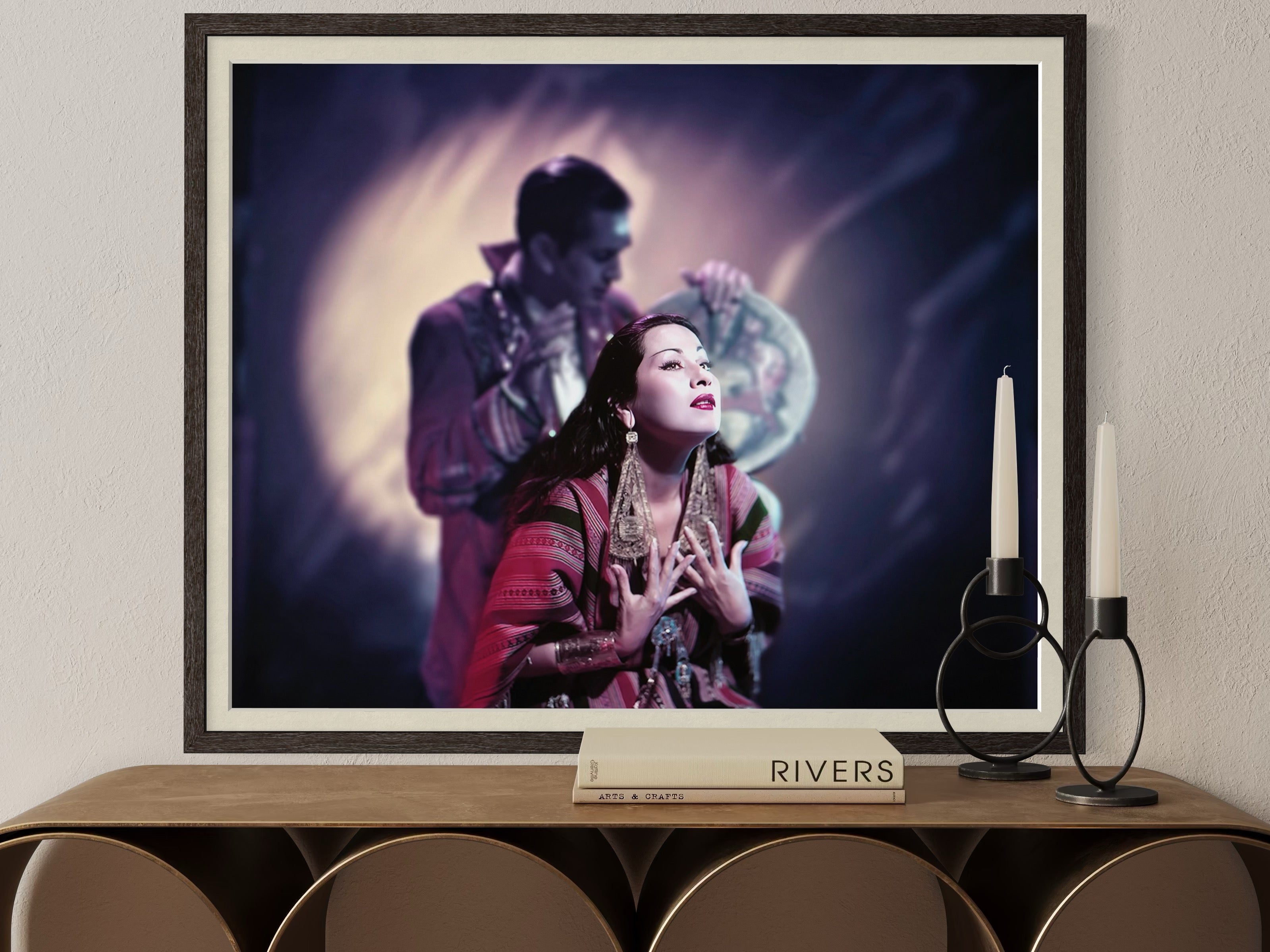 Framed artwork of a woman and a man on a wall above a wooden console table.