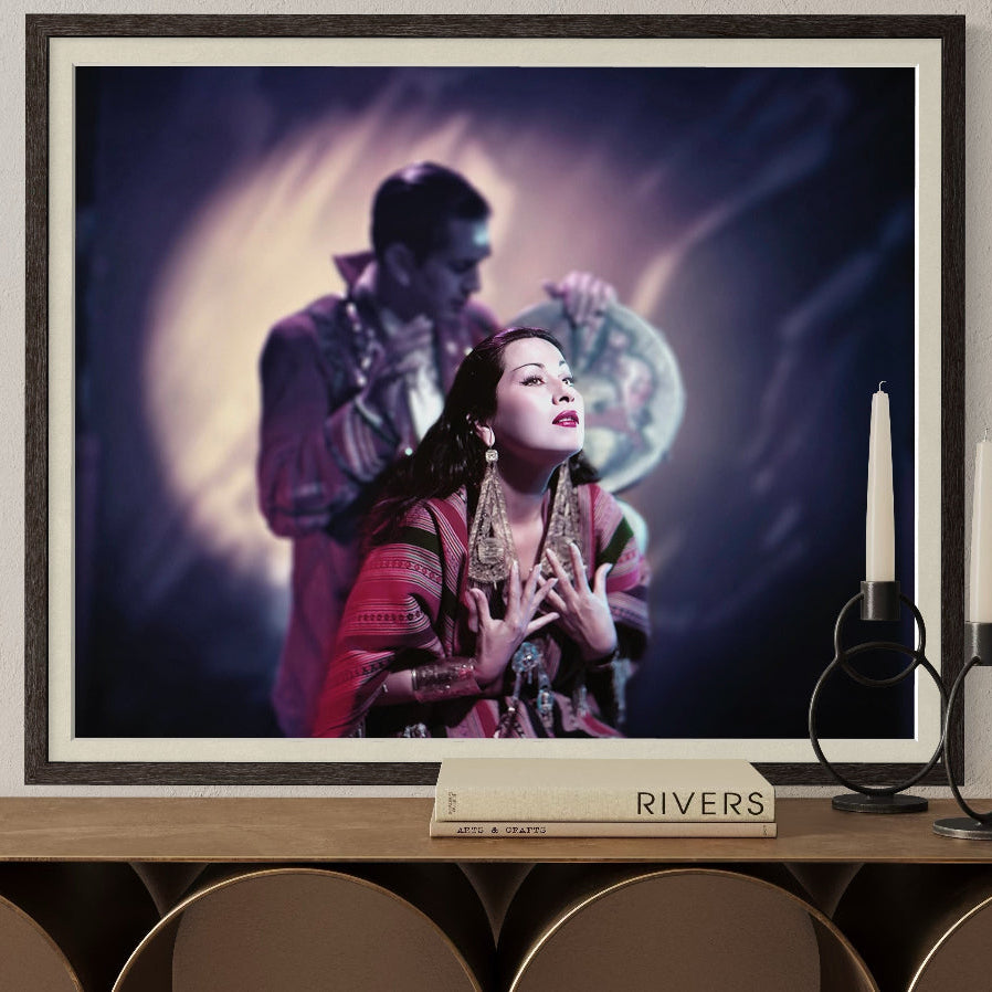 Framed artwork of a woman and a man on a wall above a wooden console table.