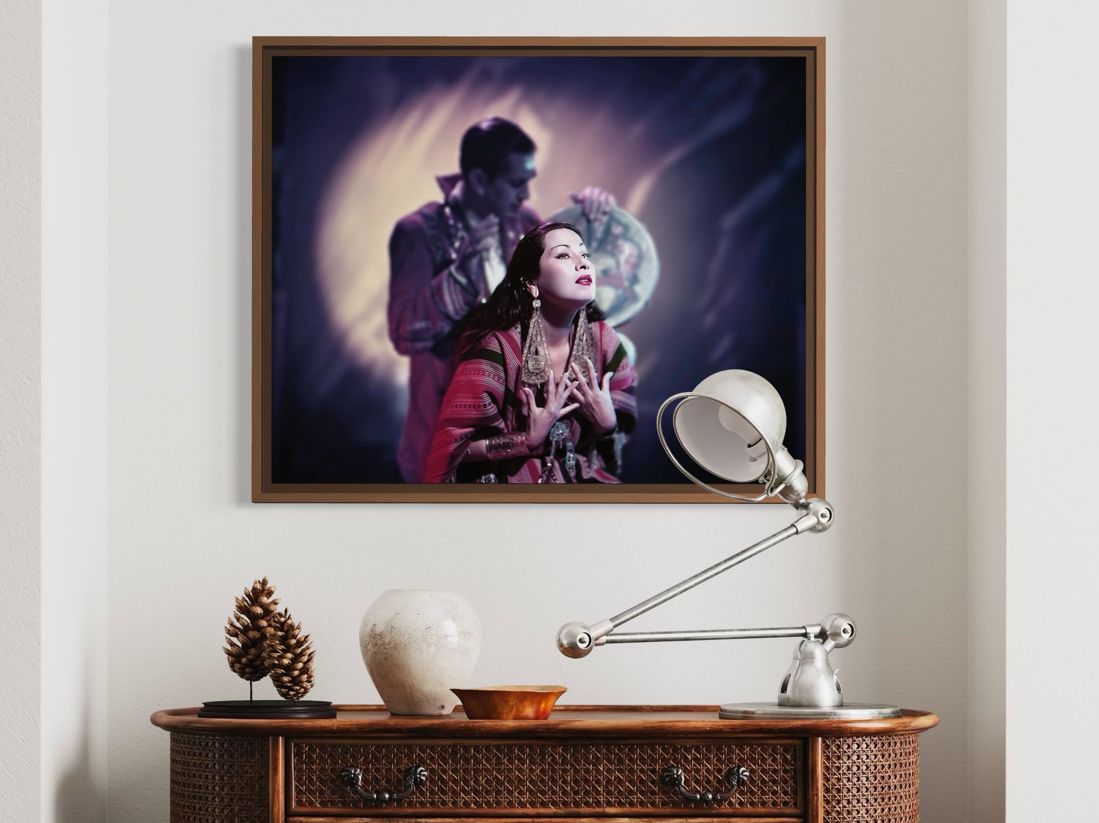 Framed artwork of a couple on a wall above a wooden console table with decorative items.