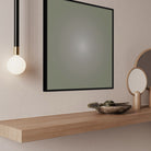 Modern interior with a mirror, light fixture, and decorative items on a wooden shelf.