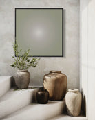 Decorative vases and a plant on a ledge with a framed abstract art above against a textured wall.