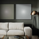 Modern living room with a beige sofa, gold lamp, and framed artwork on a dark wall.