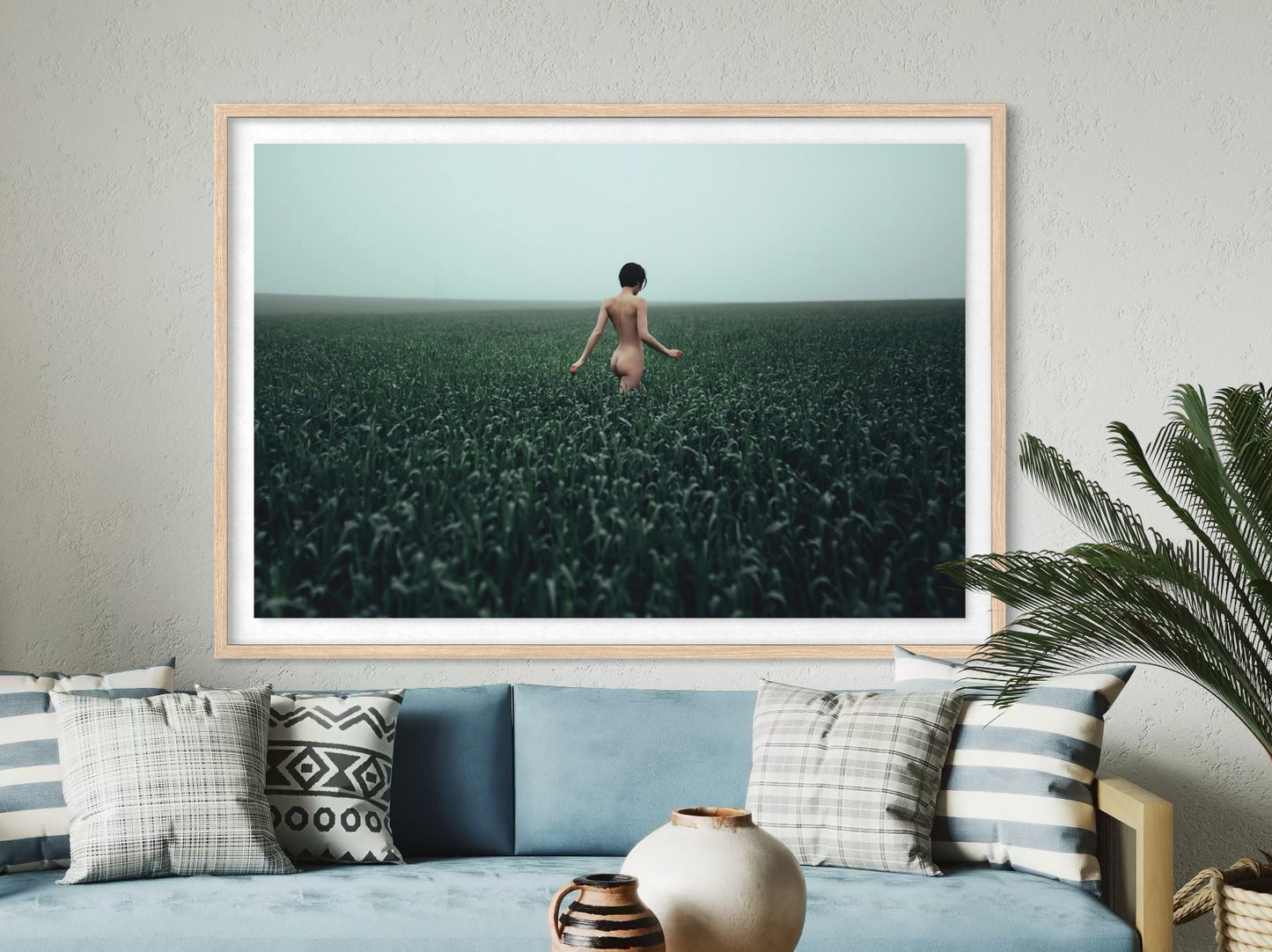 Framed artwork of a person standing in a field on a wall above a sofa.