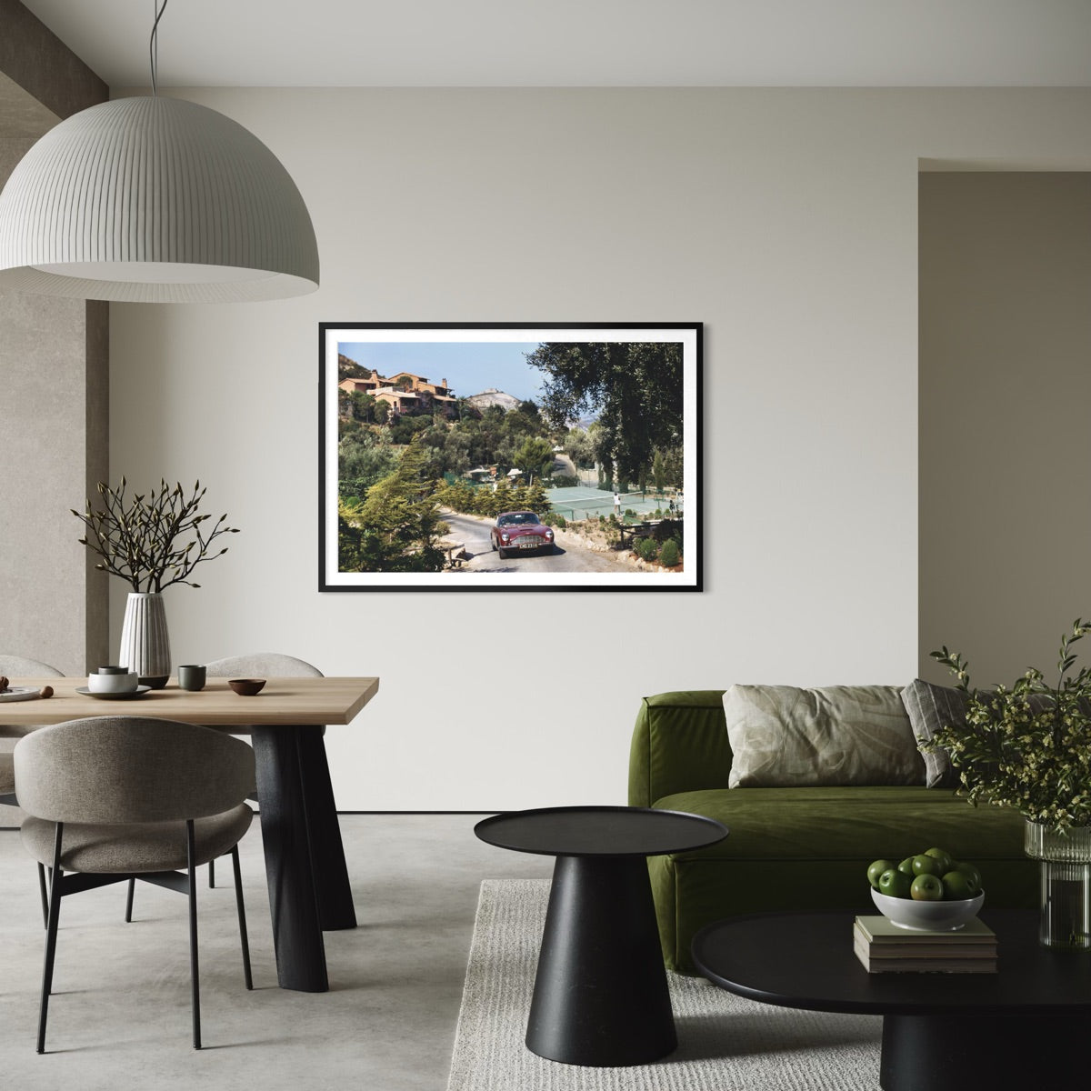 A framed landscape art print of a scenic coastal road with a purple car, displayed on a light beige wall in a modern, stylishly decorated living room.