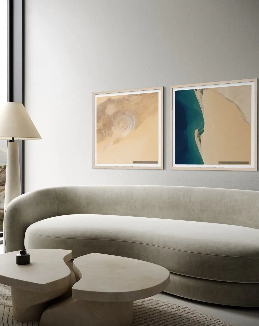 A modern living room scene featuring two framed abstract art prints hanging on a light gray wall above a curved light gray sofa. The left print is beige and cream with a spiral motif, and the right print shows a teal and beige abstract landscape.