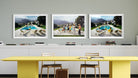 A set of three framed art prints depicting outdoor poolside scenes, displayed on a gray wall above a modern yellow table and white chairs.