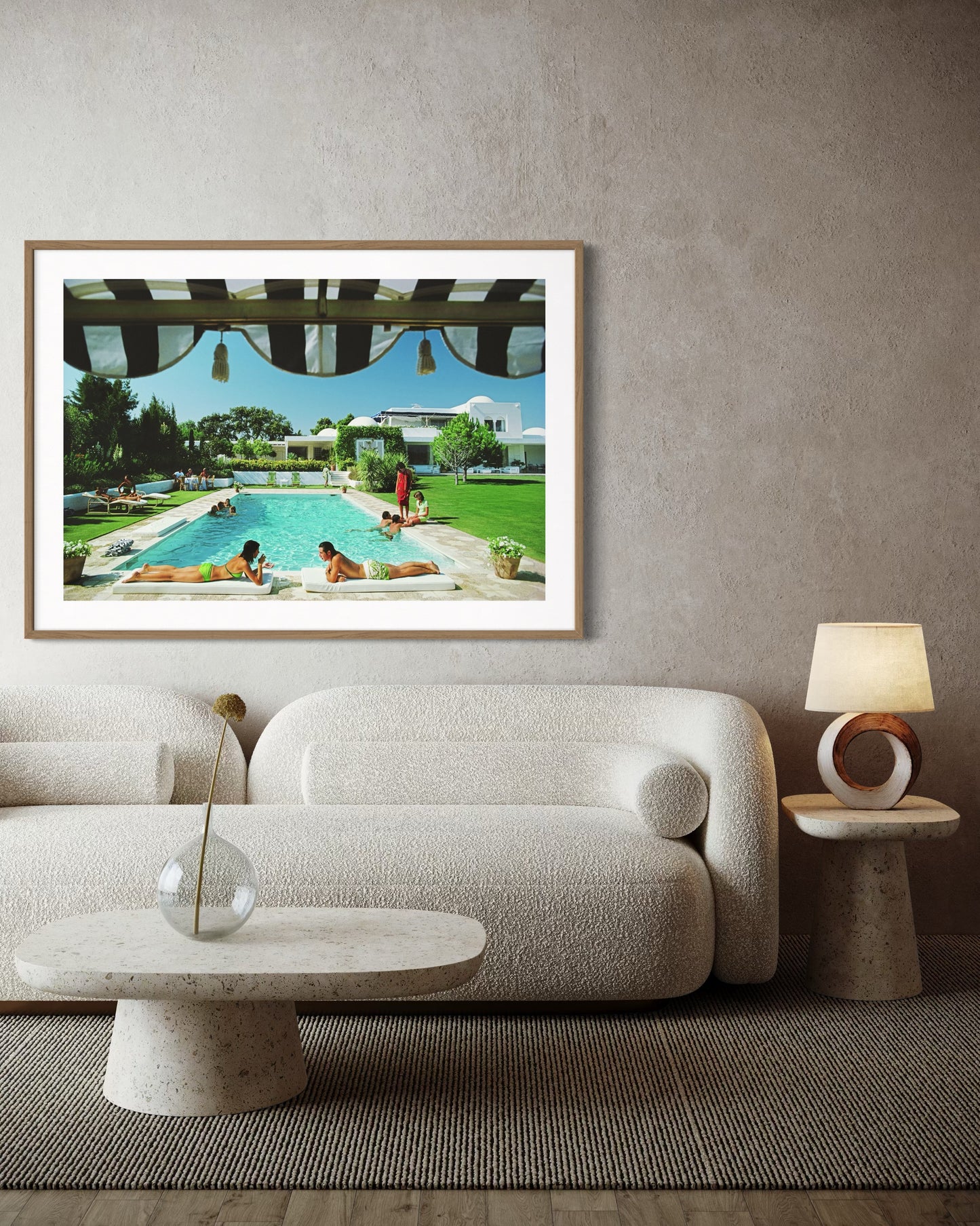 Framed artwork of a pool scene on a wall above a sofa in a living room.