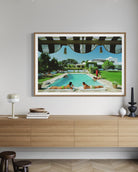 Framed artwork of a pool scene on a wall above a wooden cabinet.