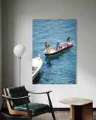 Canvas print of people on a boat hanging on a wall above a chair.