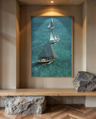 Framed artwork of sailboats on a wall above a wooden shelf.