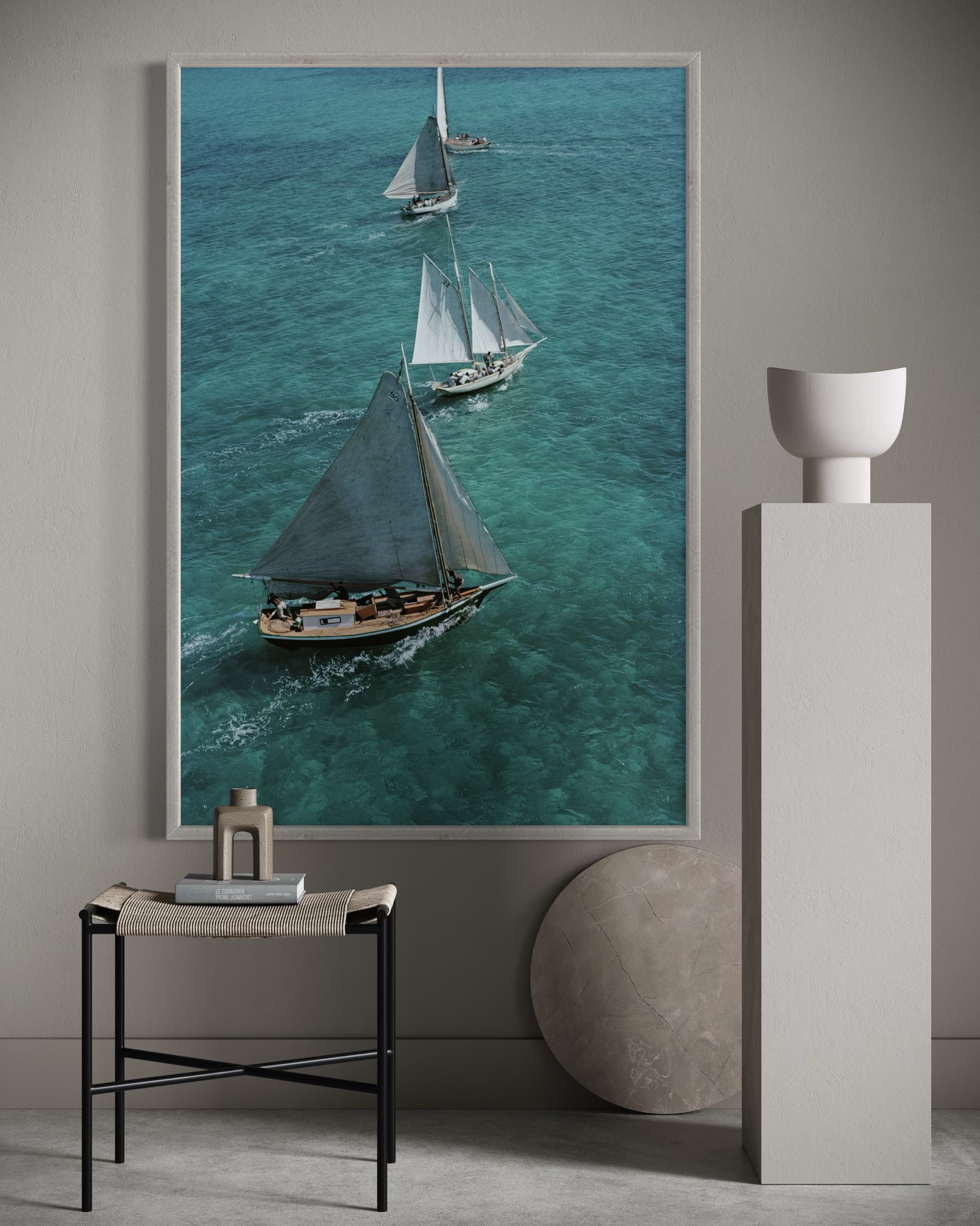 Framed artwork of sailboats on a blue ocean wall above a side table with decorative items.