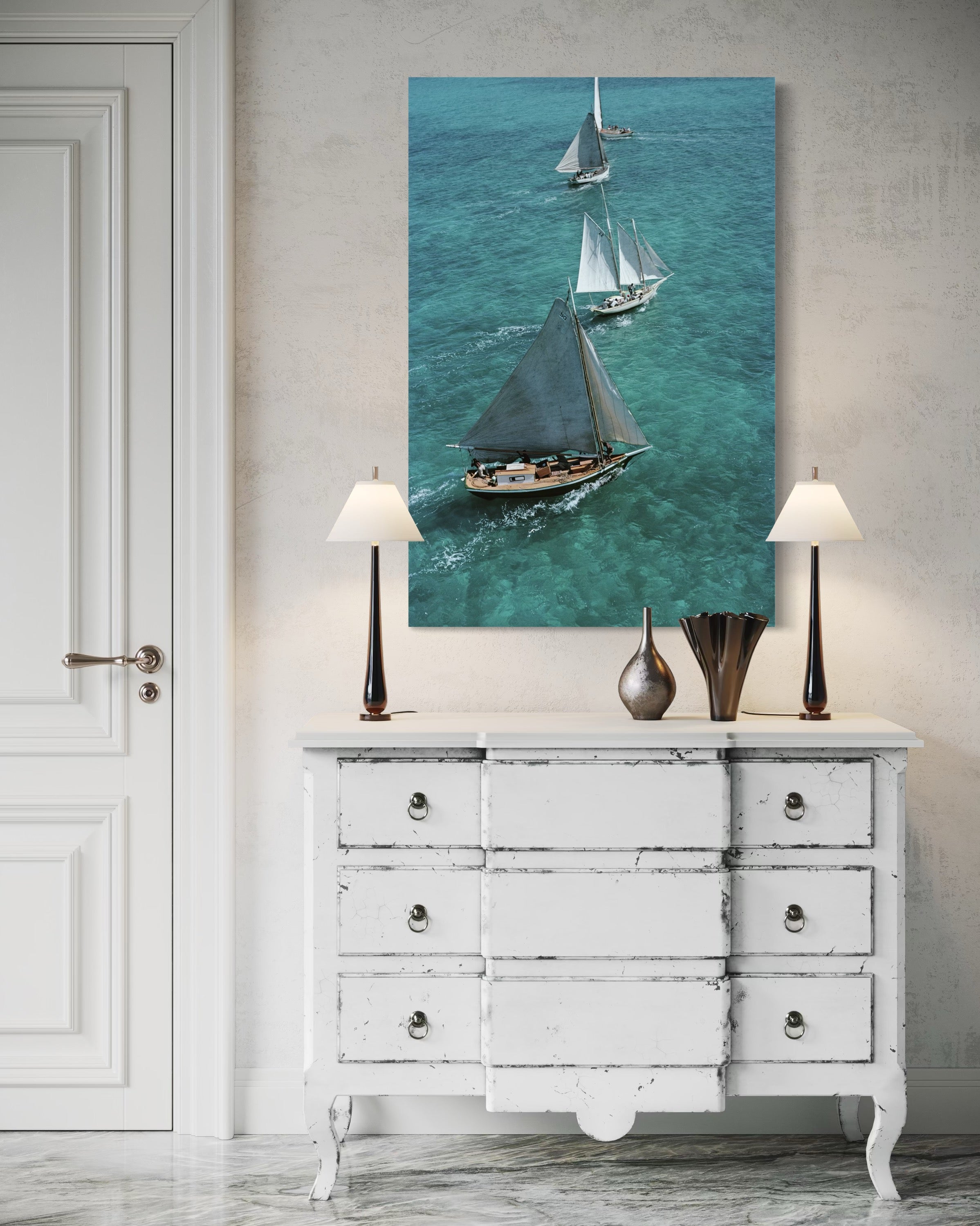 Sailing boat painting above a white dresser with lamps on either side.
