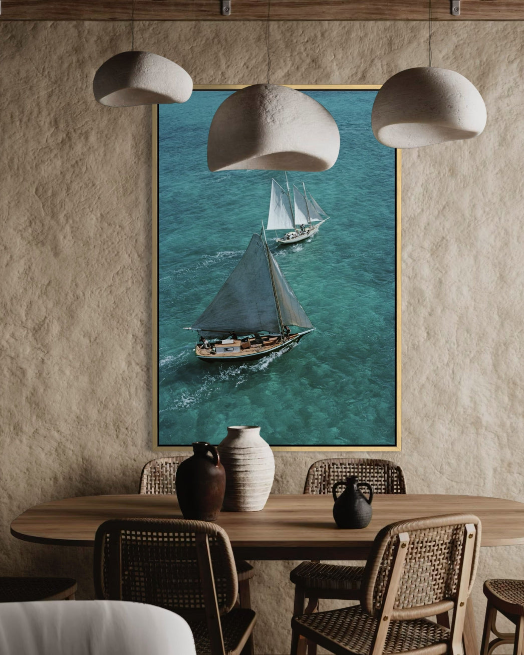 Framed artwork of sailboats on a wall above a dining table with chairs.
