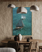Framed artwork of sailboats on a wall above a dining table with chairs.