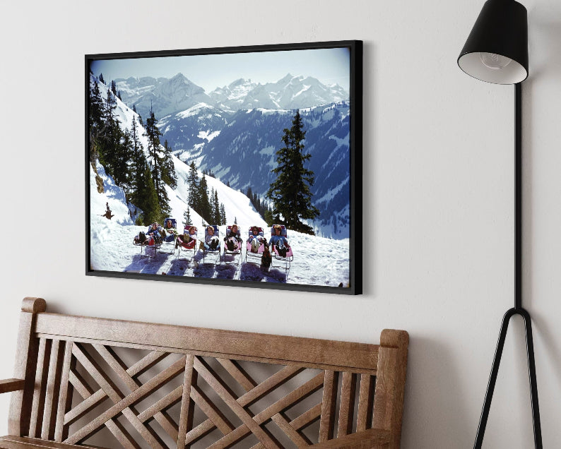 Lounging in Gstaad by Slim Aarons displayed above a modern fireplace in a cozy alpine-inspired living room, framed with The Picturalist custom framing, ideal for designer-grade wall decor, art for commercial spaces, and curated art for hotels and ski properties.