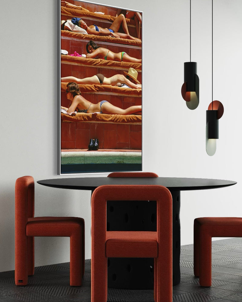Modern dining area with red chairs and a round table, featuring a large mirror on the wall.