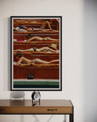 Framed artwork of women sunbathing on a beach with a clock on a table below.