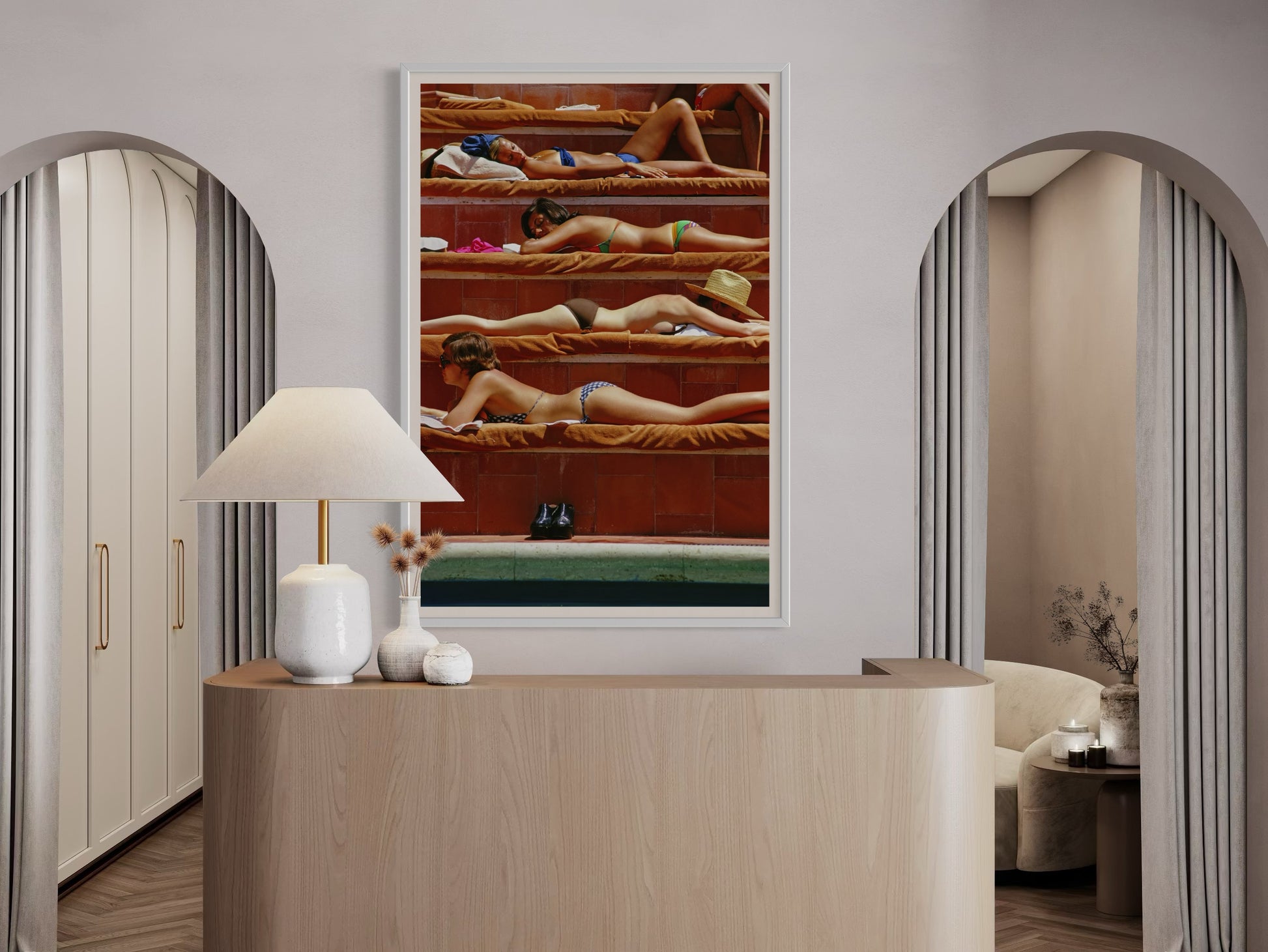 Modern interior with a framed artwork of women in swimsuits on a red background, a lamp, and a vase.