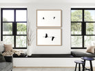 Living room with framed artwork of birds on a white wall, large windows, and modern furniture.