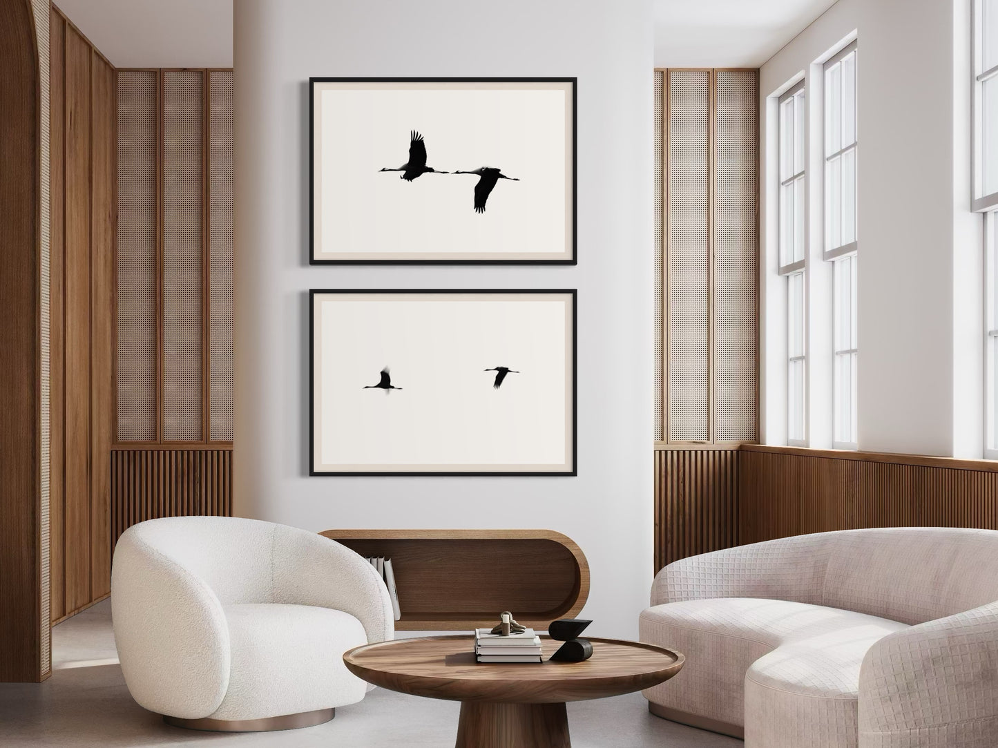 Modern living room with white chairs, a wooden table, and framed black and white artwork on the wall.