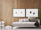 Two framed black and white artworks of birds on a wooden wall above a sofa.