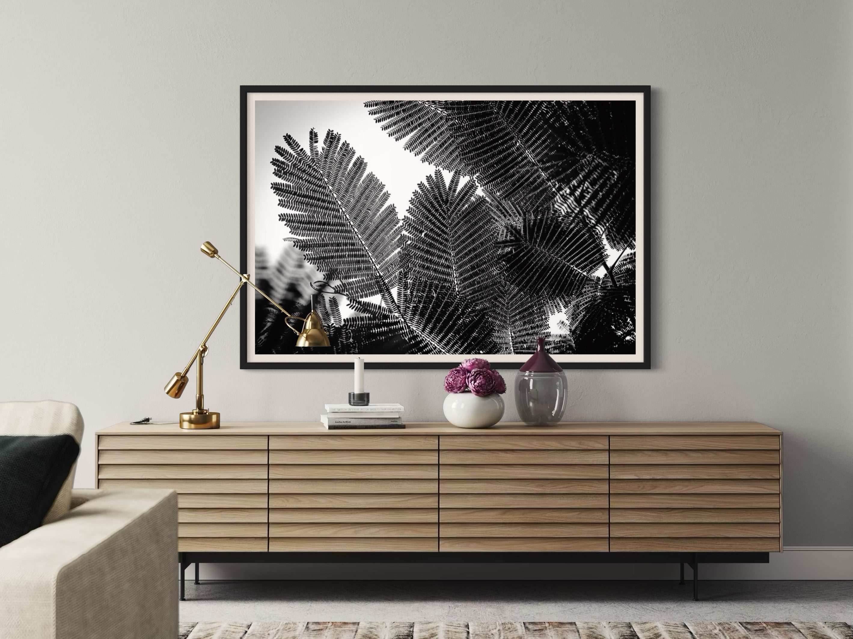 Framed black and white leaf print above a wooden console table in a living room.