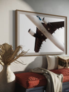 Framed photograph of an airplane on a wall above a sofa with decorative elements.