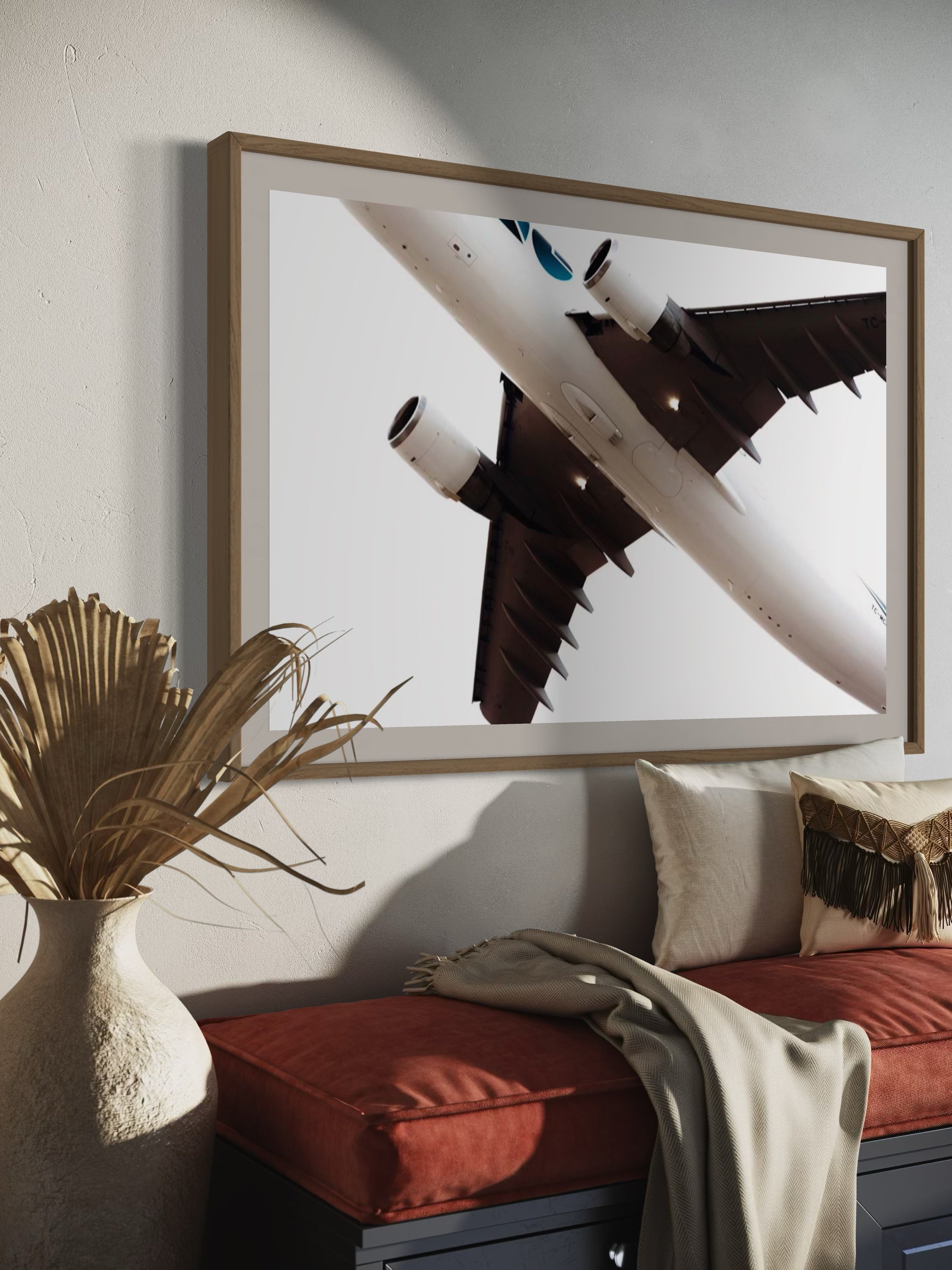 Framed photograph of an airplane on a wall above a sofa with decorative elements.