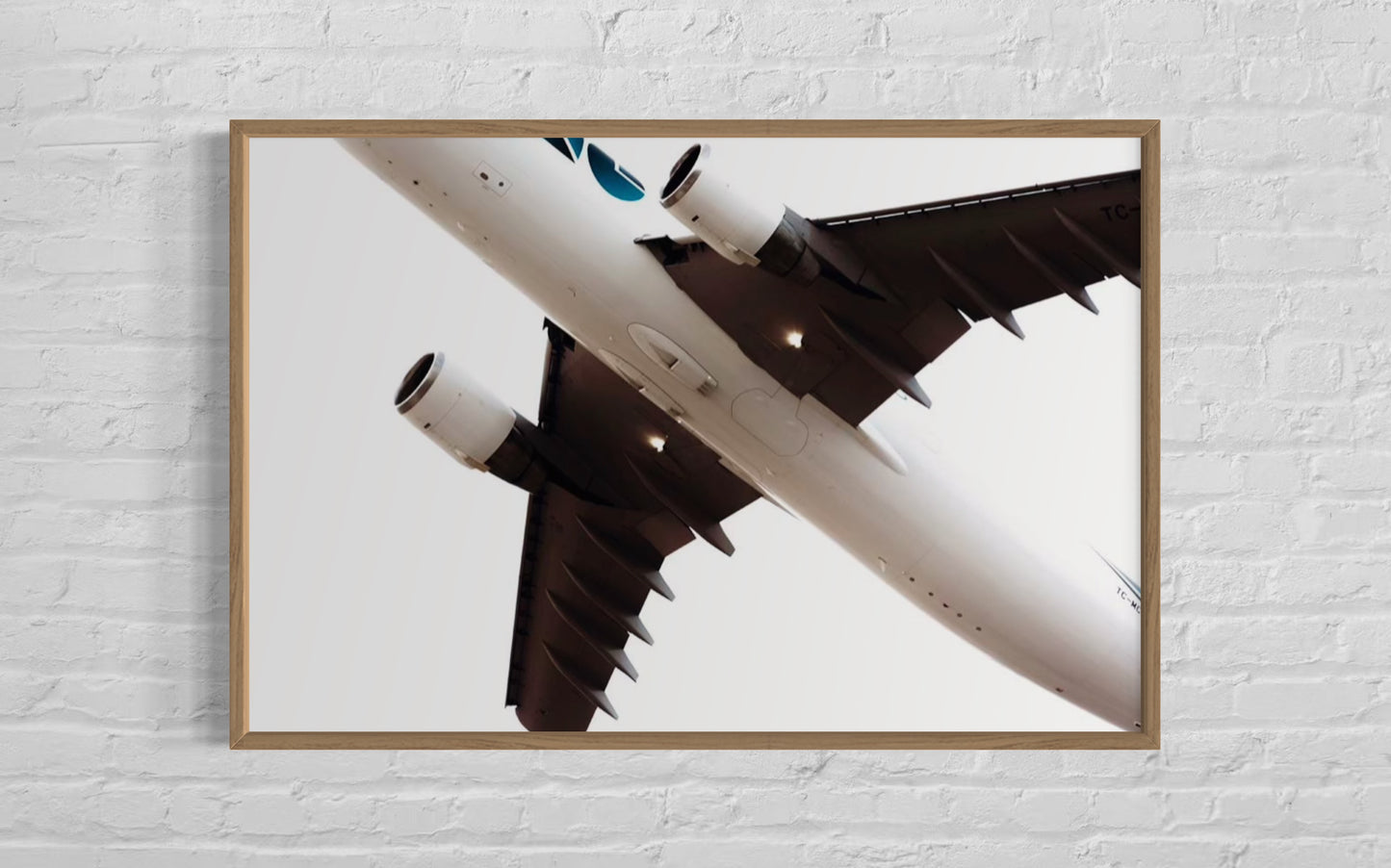 Framed photograph of an airplane on a white brick wall