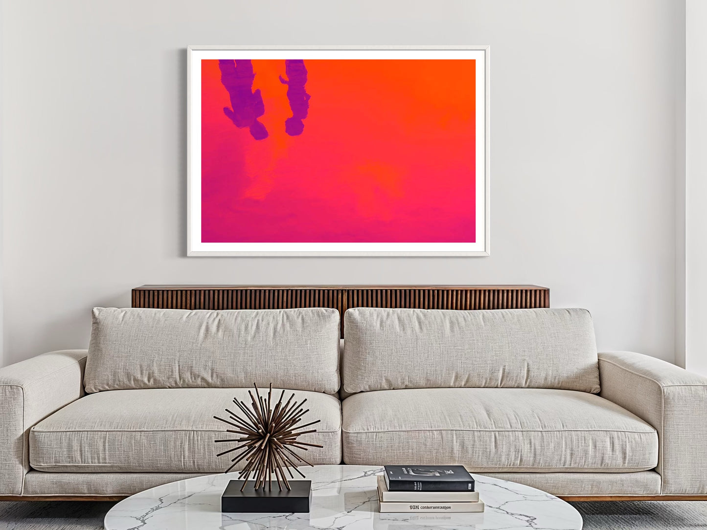 Modern living room with a beige sofa, abstract art on the wall, and decorative items on a coffee table.