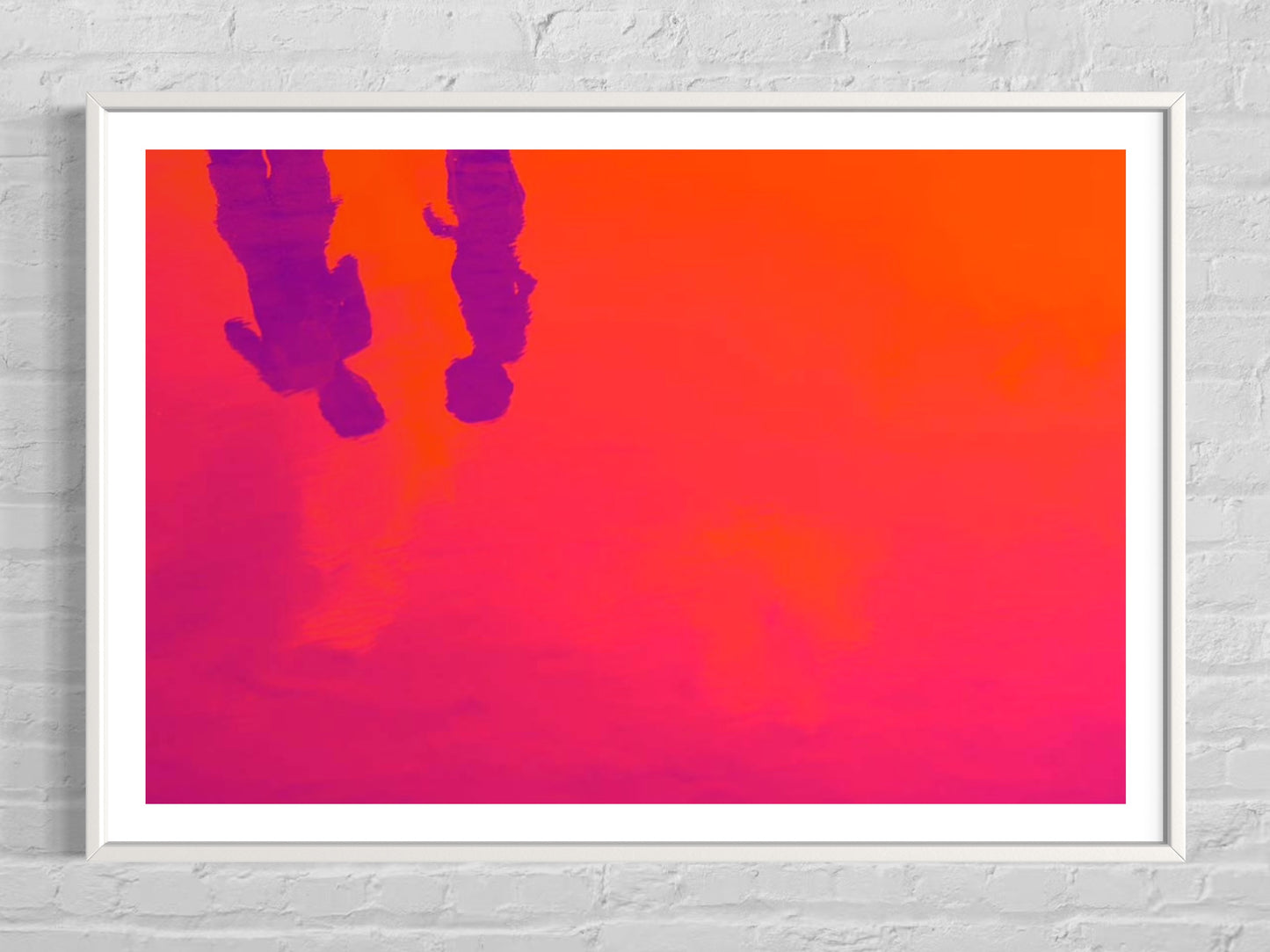 Framed artwork with a pink and orange gradient background and silhouettes of two people.