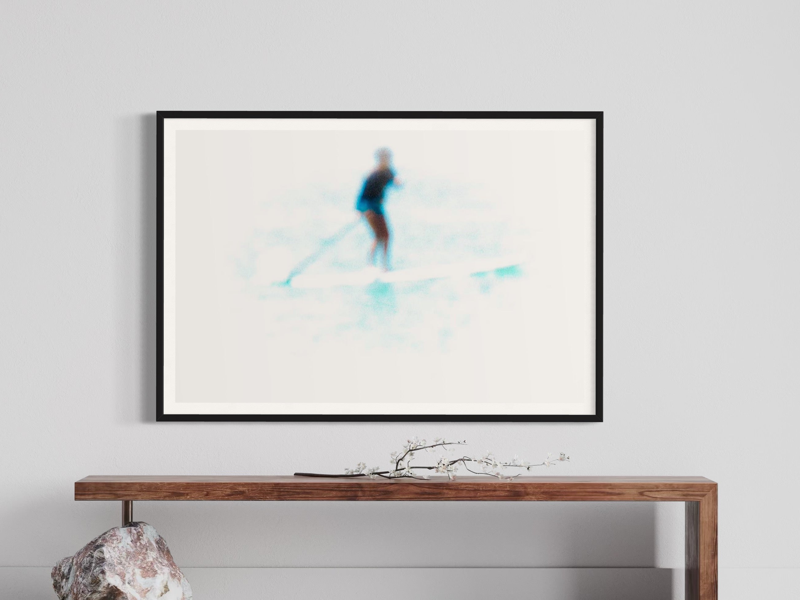 Framed artwork of a skier on a white background, displayed above a wooden console table.