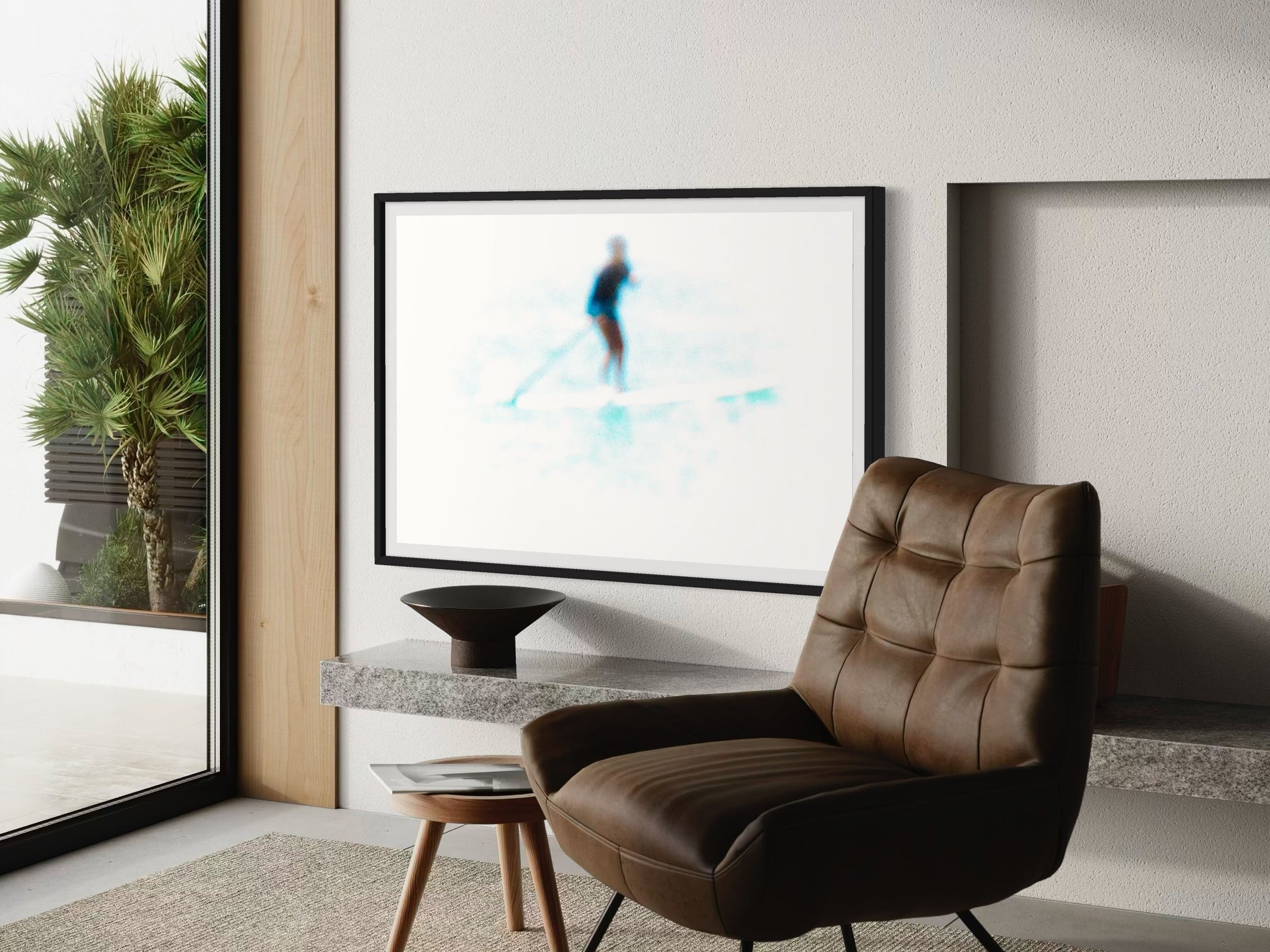 Modern living room with a brown leather chair, framed artwork, and a plant.