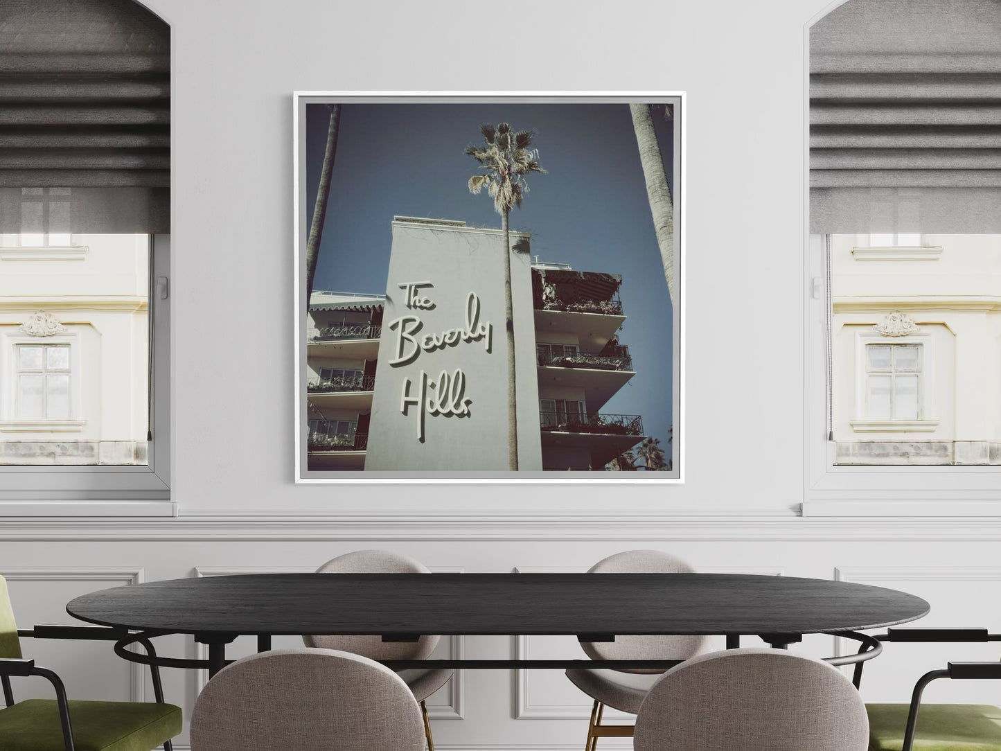 Framed artwork of the Beverly Hills hotel on a wall above a dining table.
