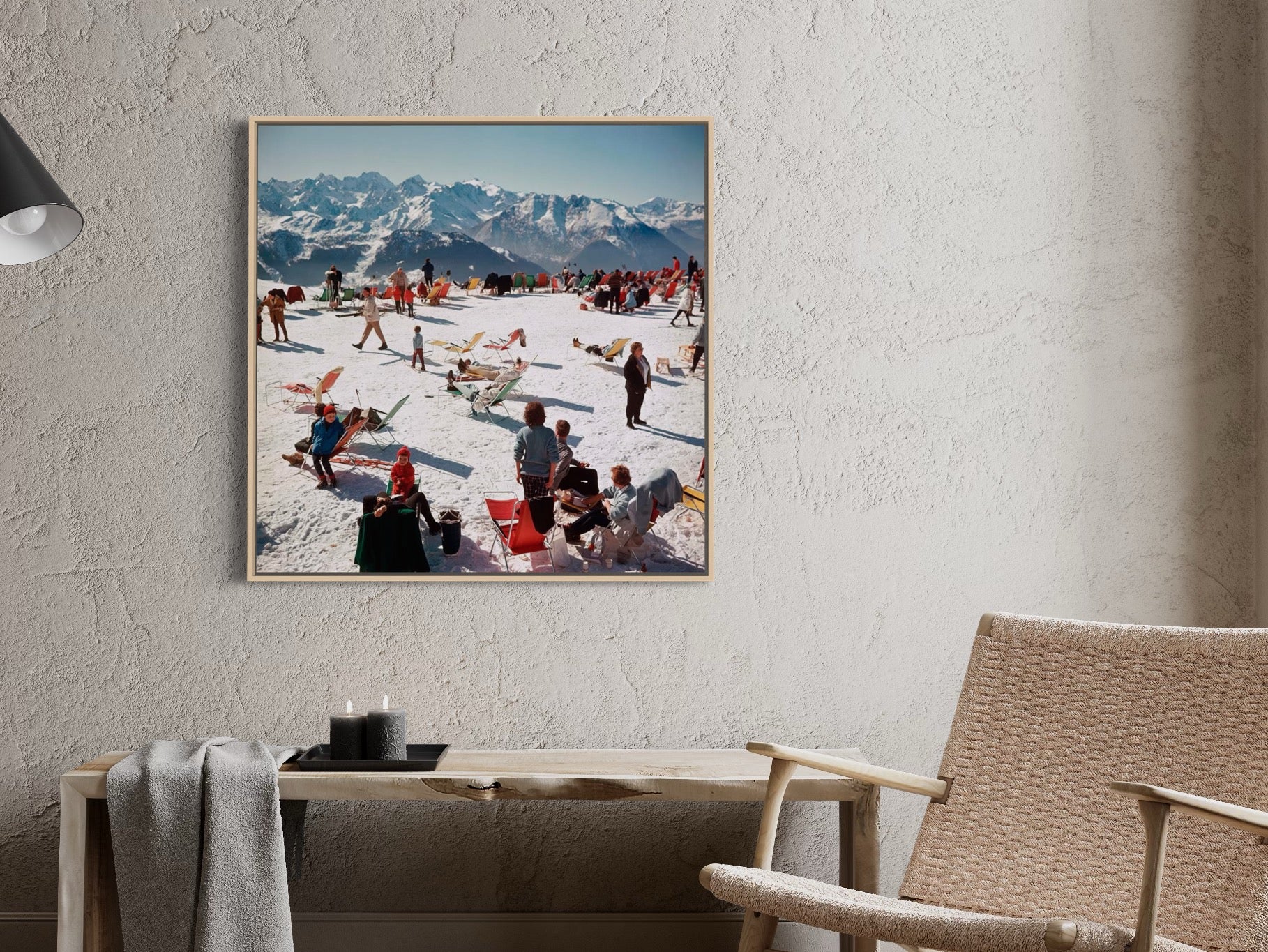 Framed photograph of a snowy mountain scene with people on a wall in a room with a chair and table.