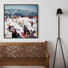 Framed photograph of a snowy mountain scene with people on a wall above a wooden bench.