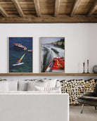 Living room with two framed pictures of boats on a wall, a white sofa, and a wooden shelf.